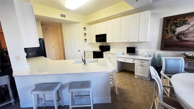 kitchen with white cabinets, a kitchen breakfast bar, black appliances, and kitchen peninsula