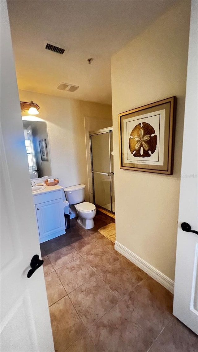 bathroom featuring a shower with shower door, vanity, toilet, and tile patterned flooring