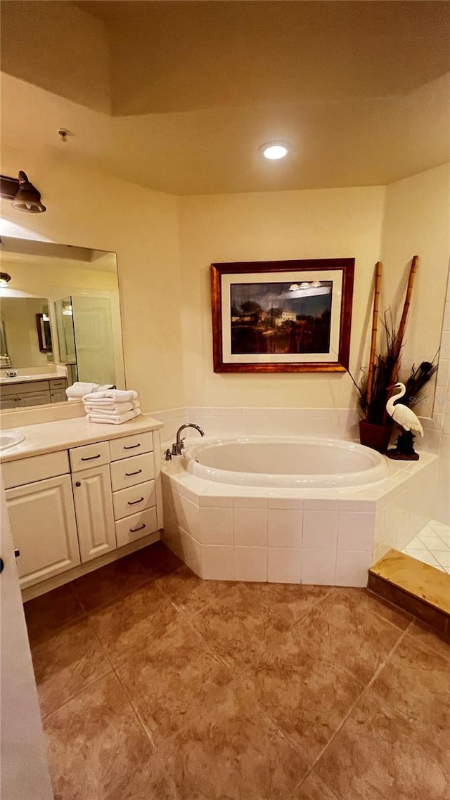 bathroom with tiled bath, vanity, and tile patterned floors