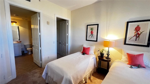 bedroom with ensuite bathroom and dark colored carpet