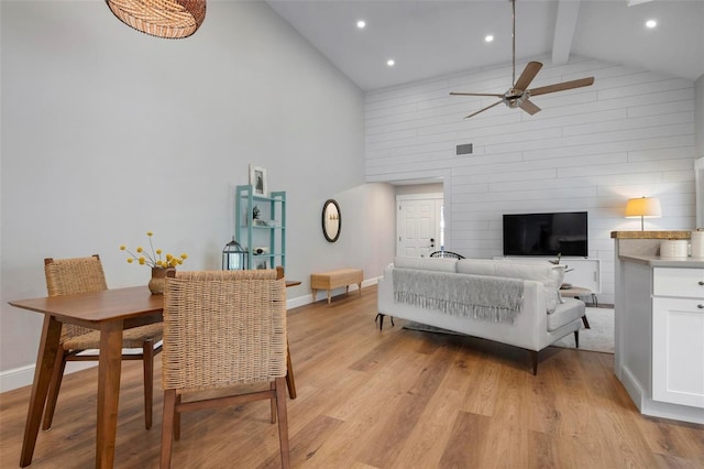 dining room featuring baseboards, a ceiling fan, light wood-style floors, high vaulted ceiling, and beam ceiling