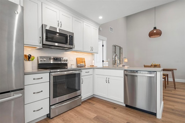 kitchen featuring stainless steel appliances, white cabinetry, sink, kitchen peninsula, and light wood-type flooring