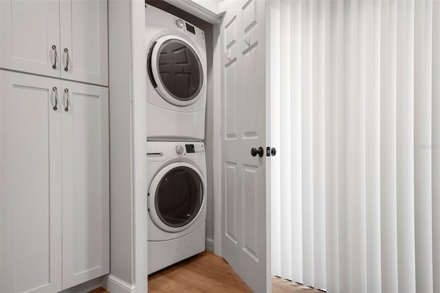 clothes washing area with stacked washer and dryer, laundry area, and light wood-style floors