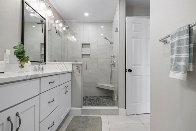 bathroom with a shower with shower door, vanity, and tile patterned floors