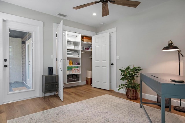 office with light wood-type flooring and ceiling fan