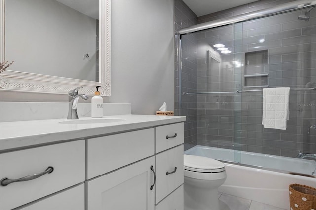 bathroom featuring combined bath / shower with glass door, vanity, toilet, and tile patterned floors