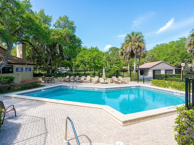 pool with a patio area and fence