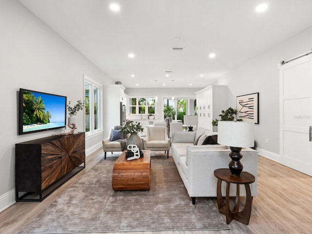 living room with light hardwood / wood-style floors, a barn door, and a healthy amount of sunlight