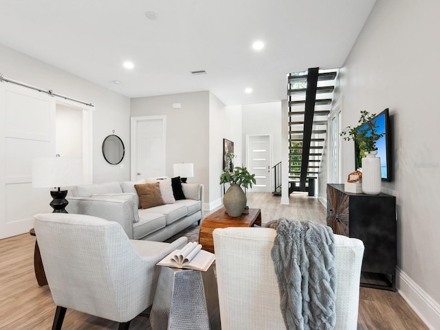 living room with a barn door and light wood-type flooring