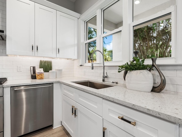 kitchen featuring white cabinets, light stone countertops, light hardwood / wood-style flooring, dishwasher, and sink