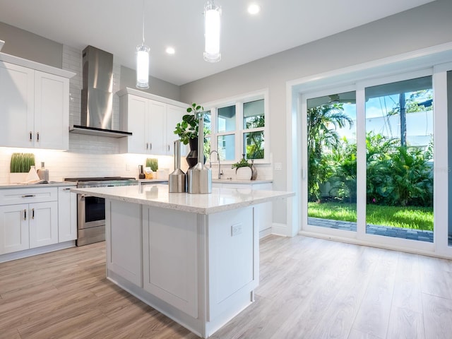 kitchen featuring white cabinetry, pendant lighting, wall chimney exhaust hood, and stainless steel range