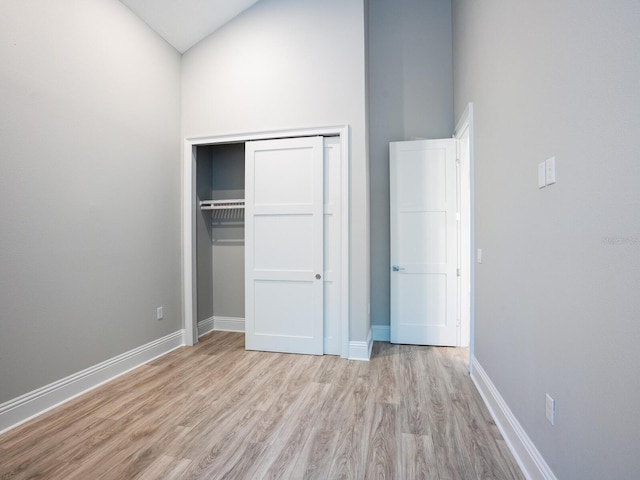 unfurnished bedroom featuring a closet, light hardwood / wood-style floors, and high vaulted ceiling