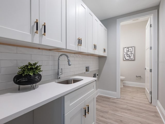 laundry room featuring cabinets, sink, light wood-type flooring, and electric dryer hookup