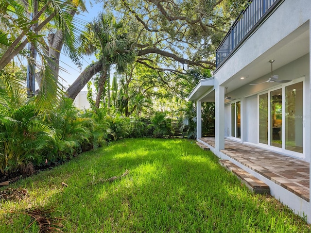 view of yard featuring a balcony, a patio, and ceiling fan