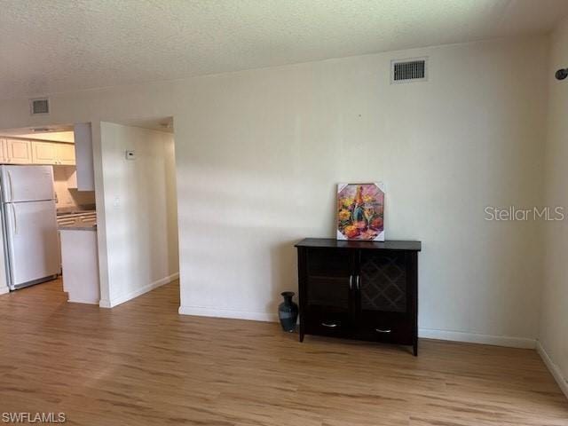 dining area with light wood finished floors, baseboards, and a textured ceiling