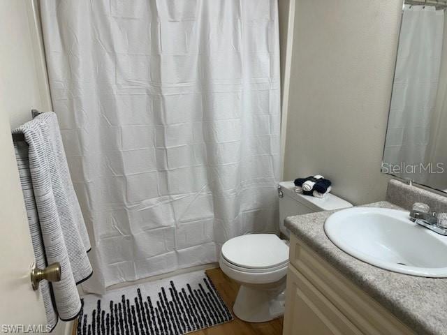 bathroom featuring vanity, curtained shower, hardwood / wood-style flooring, and toilet