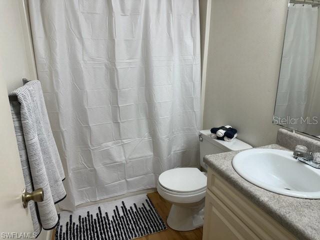 bathroom with vanity, toilet, wood finished floors, and a shower with shower curtain
