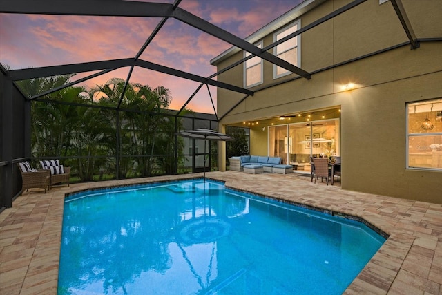 pool at dusk featuring glass enclosure, a patio, and an outdoor living space