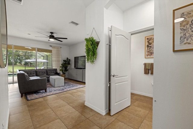 living area with a ceiling fan, visible vents, baseboards, and light tile patterned floors