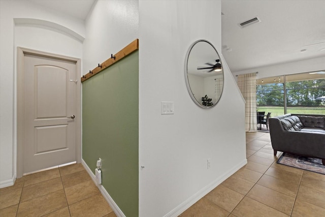 corridor featuring a barn door, light tile patterned flooring, visible vents, and baseboards