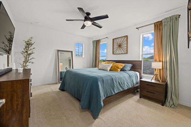 bedroom with a ceiling fan, light colored carpet, and baseboards