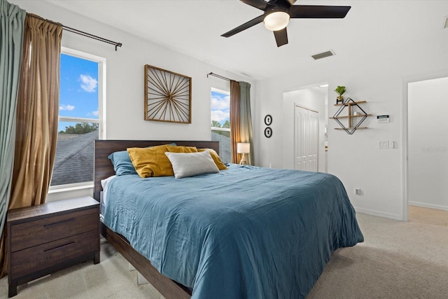 bedroom featuring baseboards, visible vents, light colored carpet, ceiling fan, and a closet