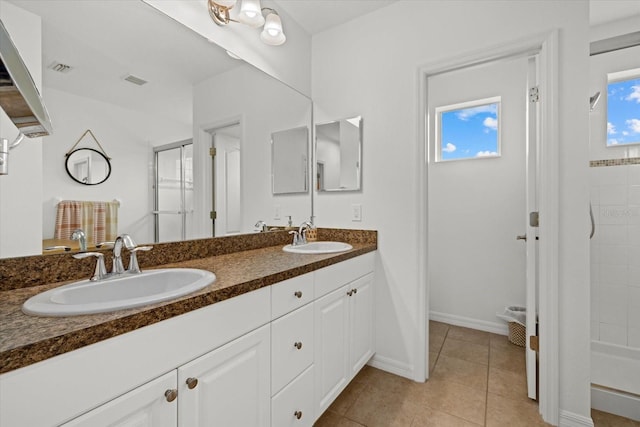 bathroom with double vanity, walk in shower, a sink, and tile patterned floors