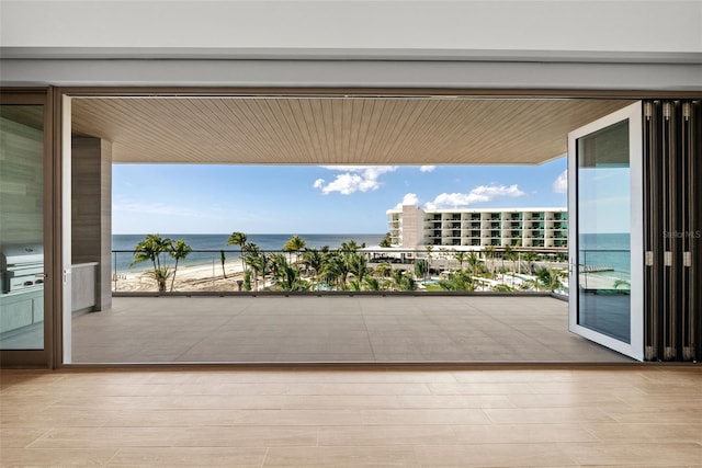 balcony featuring a grill, a view of the beach, and a water view