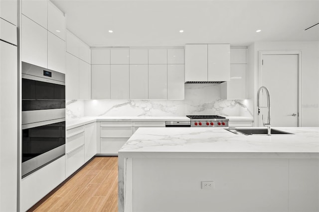 kitchen with white cabinetry, sink, light hardwood / wood-style floors, and stainless steel appliances