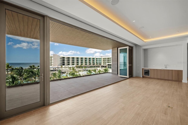 doorway featuring a water view, a wall of windows, and light hardwood / wood-style flooring