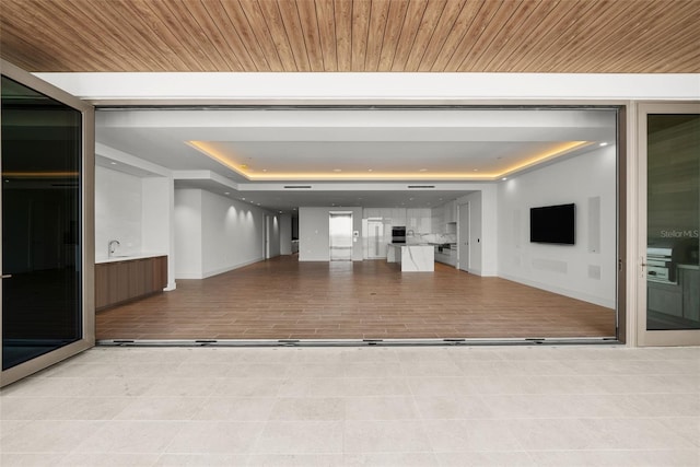 spare room featuring light hardwood / wood-style floors, sink, a raised ceiling, and wooden ceiling