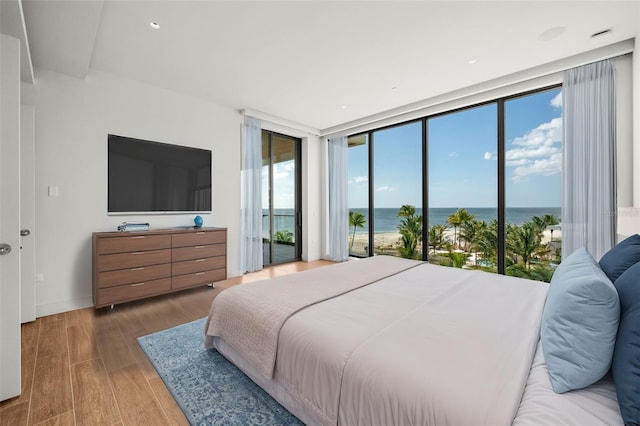 bedroom featuring hardwood / wood-style flooring, access to exterior, and a wall of windows