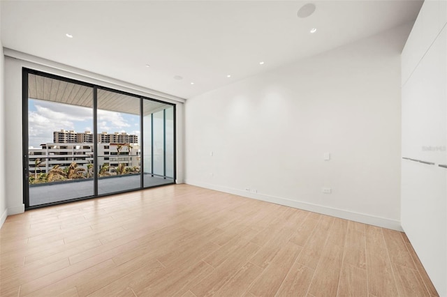 empty room with light wood-type flooring and floor to ceiling windows