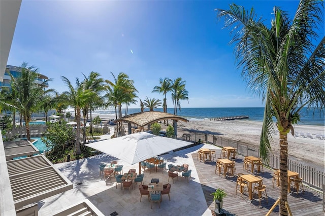 view of patio / terrace featuring a view of the beach, a water view, and a community pool