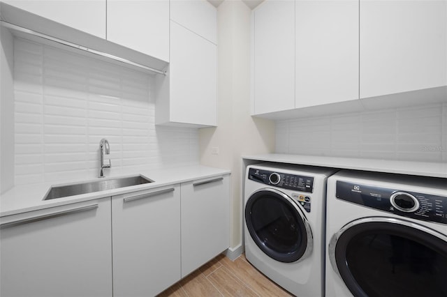 1591 Gulf Of Mexico Dr Unit 311, Longboat Key, FL 34228 - laundry room with light wood-type flooring, washing machine and clothes dryer, a sink, and cabinet space