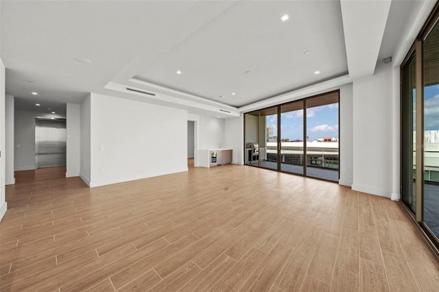 unfurnished living room with a raised ceiling and light hardwood / wood-style flooring