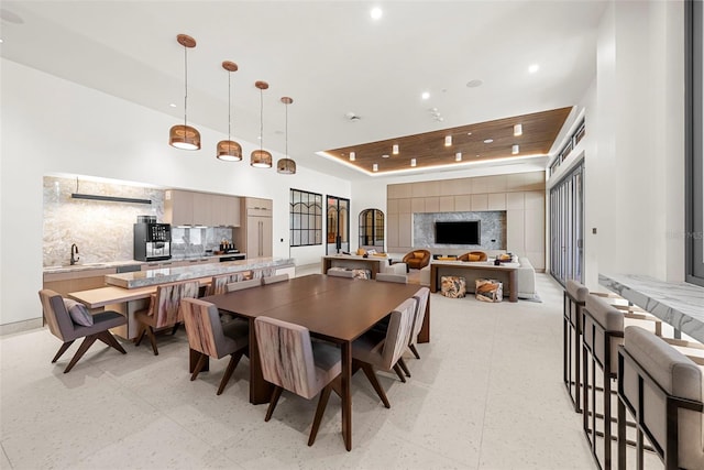 dining area featuring sink, a high ceiling, and a tray ceiling