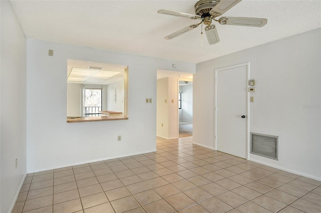 tiled empty room featuring ceiling fan and a textured ceiling