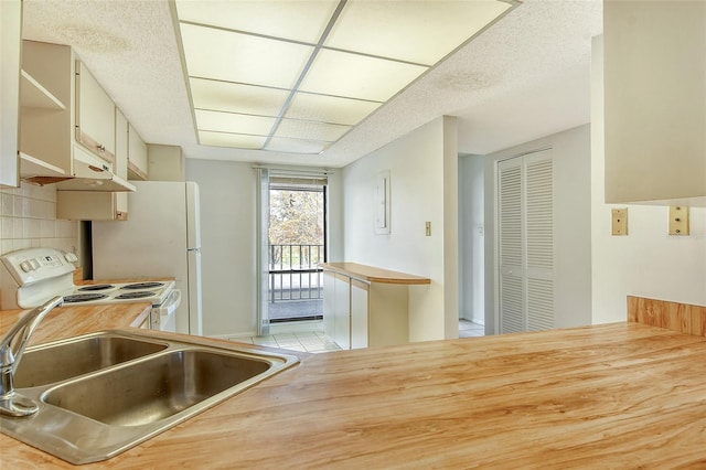 kitchen with kitchen peninsula, a textured ceiling, sink, backsplash, and white appliances