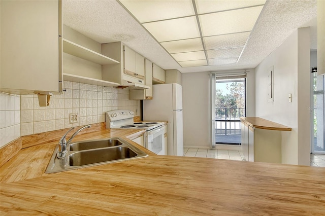 kitchen with butcher block countertops, light tile patterned floors, white appliances, and sink