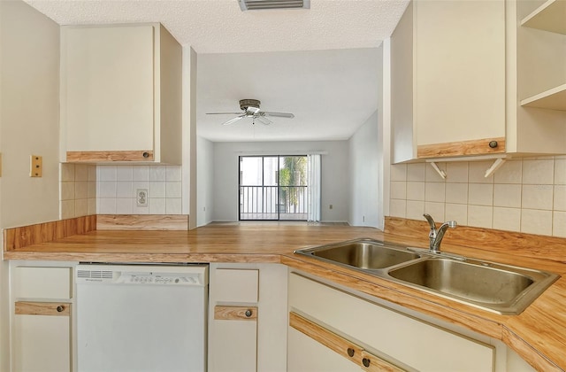 kitchen with a textured ceiling, wood counters, decorative backsplash, sink, and dishwasher