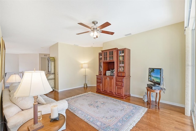 living room with light wood-type flooring and ceiling fan