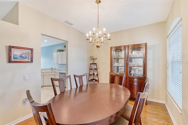 dining room with light hardwood / wood-style flooring, sink, and an inviting chandelier