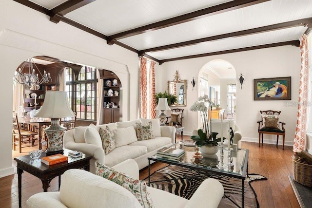 living room featuring hardwood / wood-style flooring, a notable chandelier, and beamed ceiling