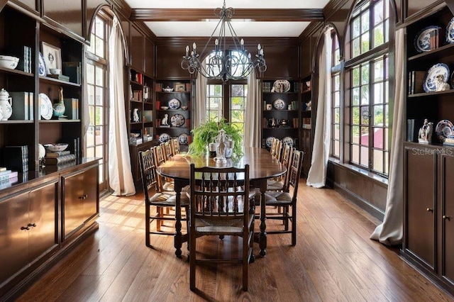 dining area featuring hardwood / wood-style floors, built in shelves, ornamental molding, and a chandelier