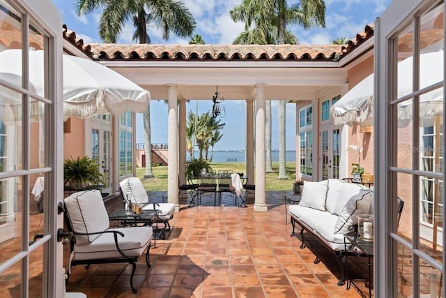 sunroom / solarium featuring a water view, plenty of natural light, and french doors