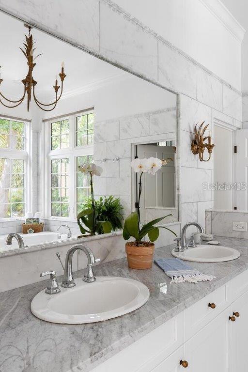 bathroom featuring tasteful backsplash, ornamental molding, vanity, and tile walls