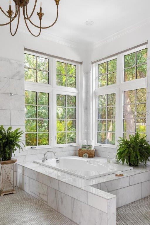 bathroom with crown molding, plenty of natural light, a relaxing tiled tub, and tile patterned flooring