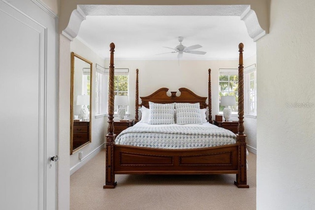 carpeted bedroom with ornamental molding and ceiling fan