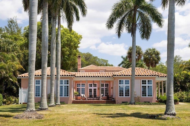 4511 Bay Shore Rd, Sarasota, FL 34234 - rear view of property with a tiled roof, a lawn, stucco siding, a chimney, and a deck